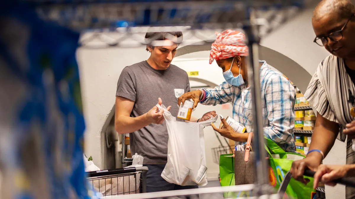 Two individuals bagging groceries at a food pantry