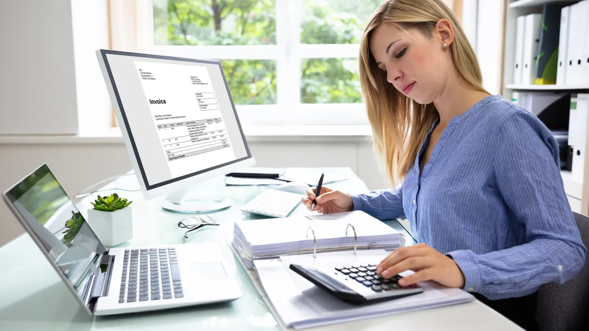 Young Businesswoman Calculating Bill In Office