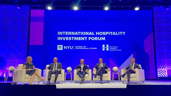 A group of executives sits on a conference stage.