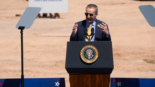 Executive Pat Gelsinger speaks at a lectern bearing the seal of the president in front of a construction worksite