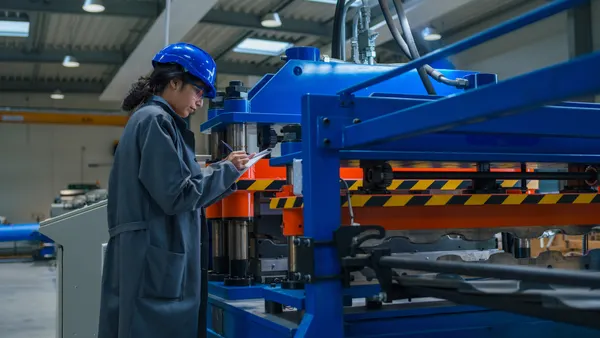 A worker in an industrial setting uses a clipboard.