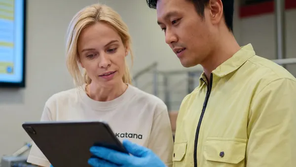 A man and woman looking at a clipboard with Katana shirts