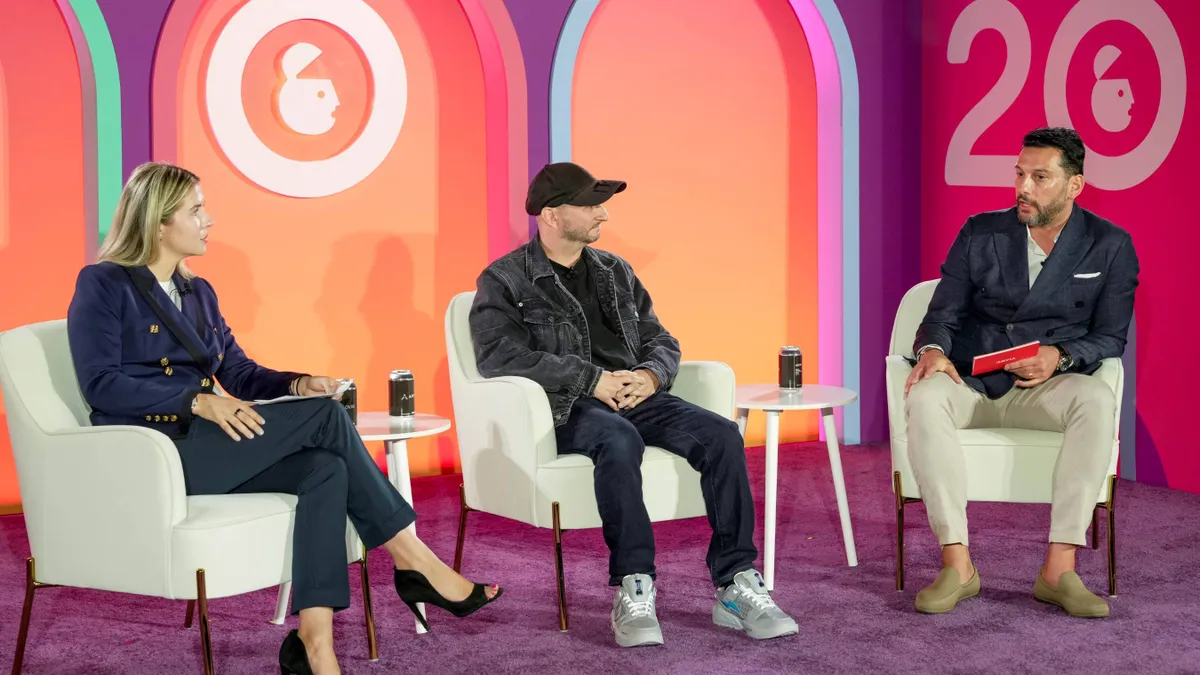 A trio of executives sit on a stage at Advertising Week New York 2024