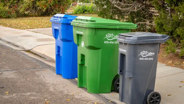 Three blue, green and gray waste carts out on a street in Fort Collins, Colorado, on pickup day for household trash, backyard trimmings and recyclable materials.