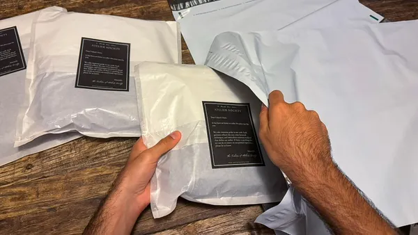 A person packages tailored items from Atelier Society.