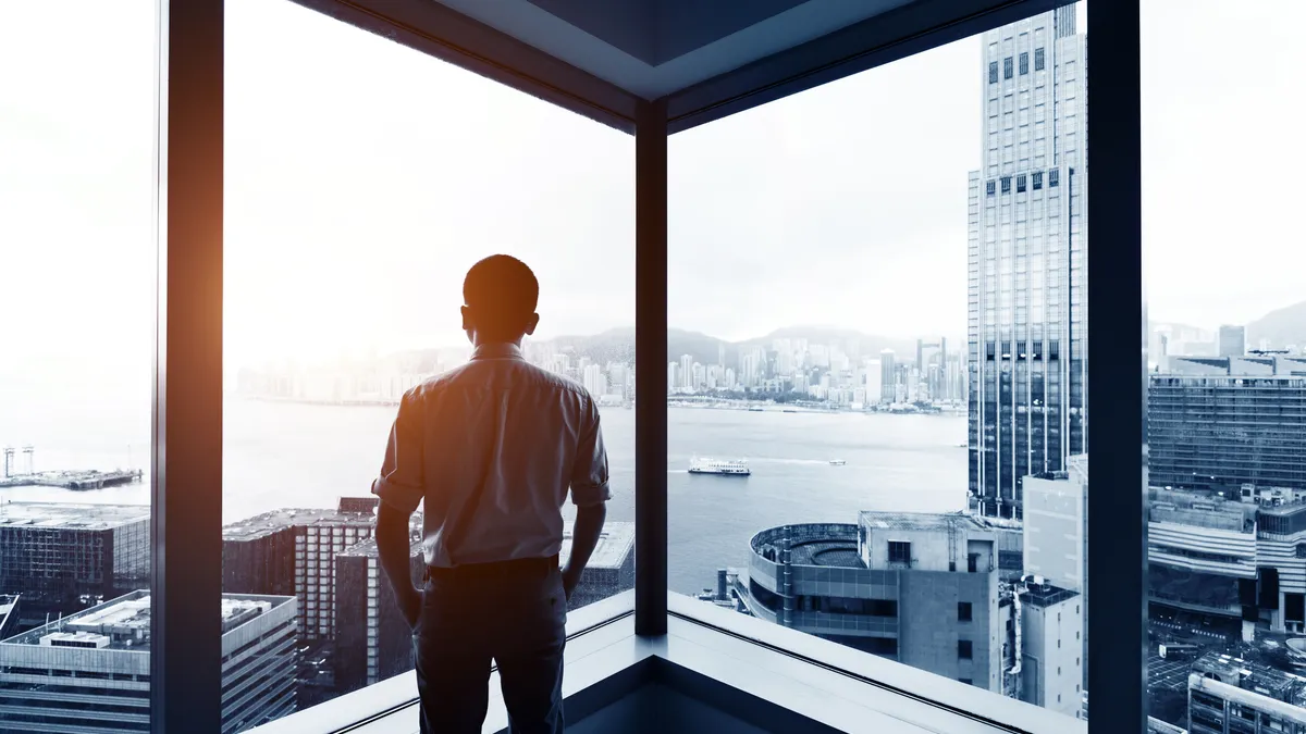 Businessman looking at city through office window