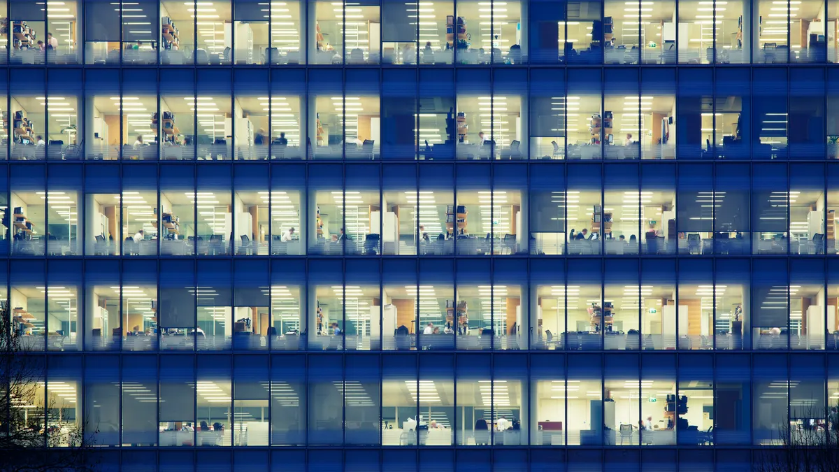 Modern office block at night revealing the daily activity of office workers themes of deadline overtime urban scene