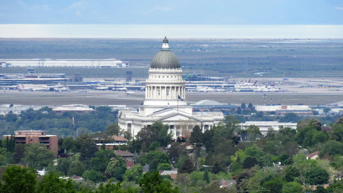 A sky-high view of a large, white domed government building with an airport in the background.