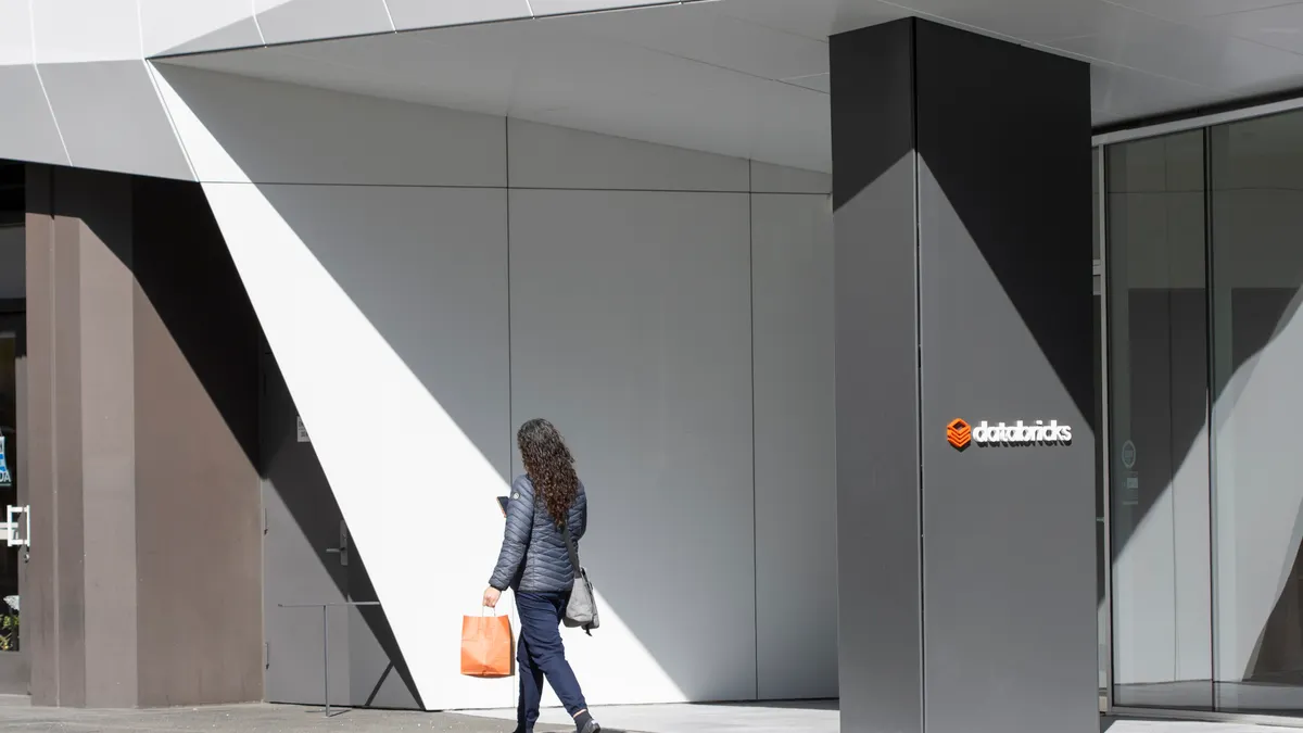 a woman walks outside of an office branded with Databricks signage