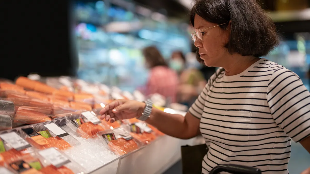 Woman choosing fresh fish at seafood aisle in the supermarket