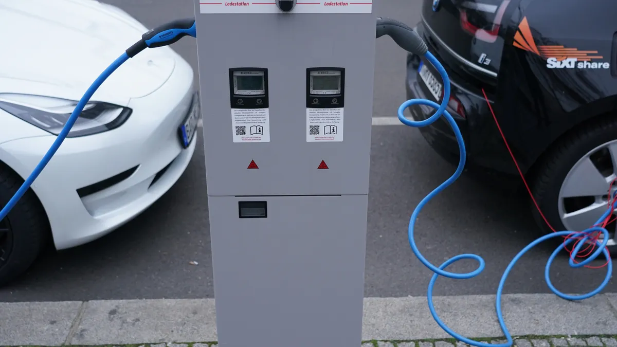 Two electric cars are plugged into a power supply unit.