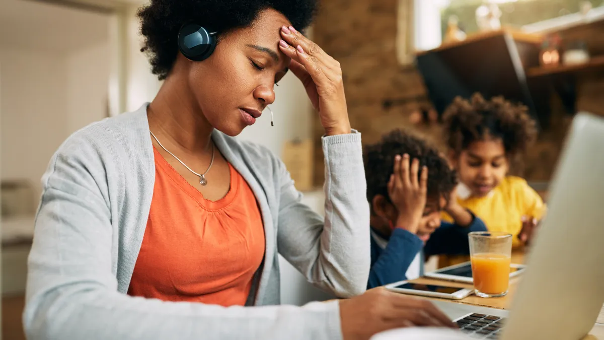 Black single mother feeling frustrated while working at home.