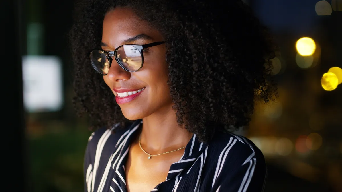 A woman with glasses smiling.