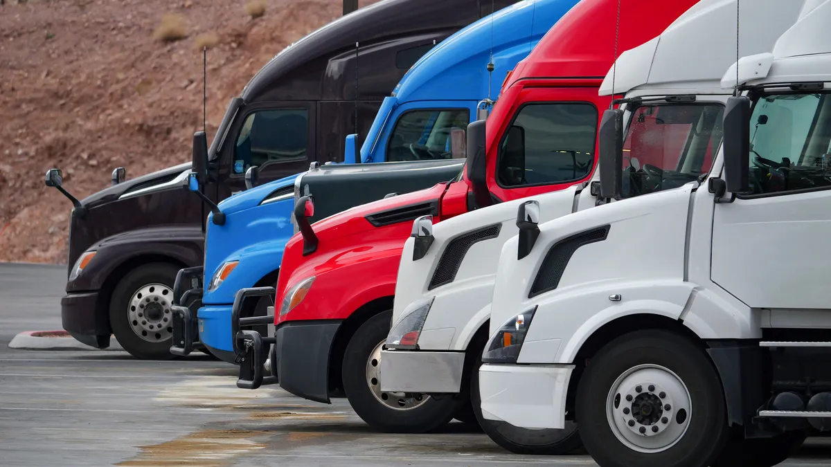 Red, blue, white and black trucks at a truck stop.