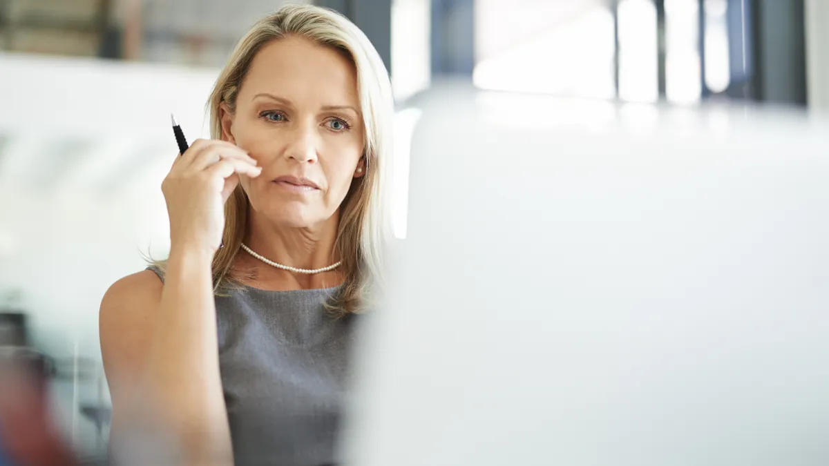 Shot of an older businesswoman, looking thoughtful as she uses a laptop in a modern office