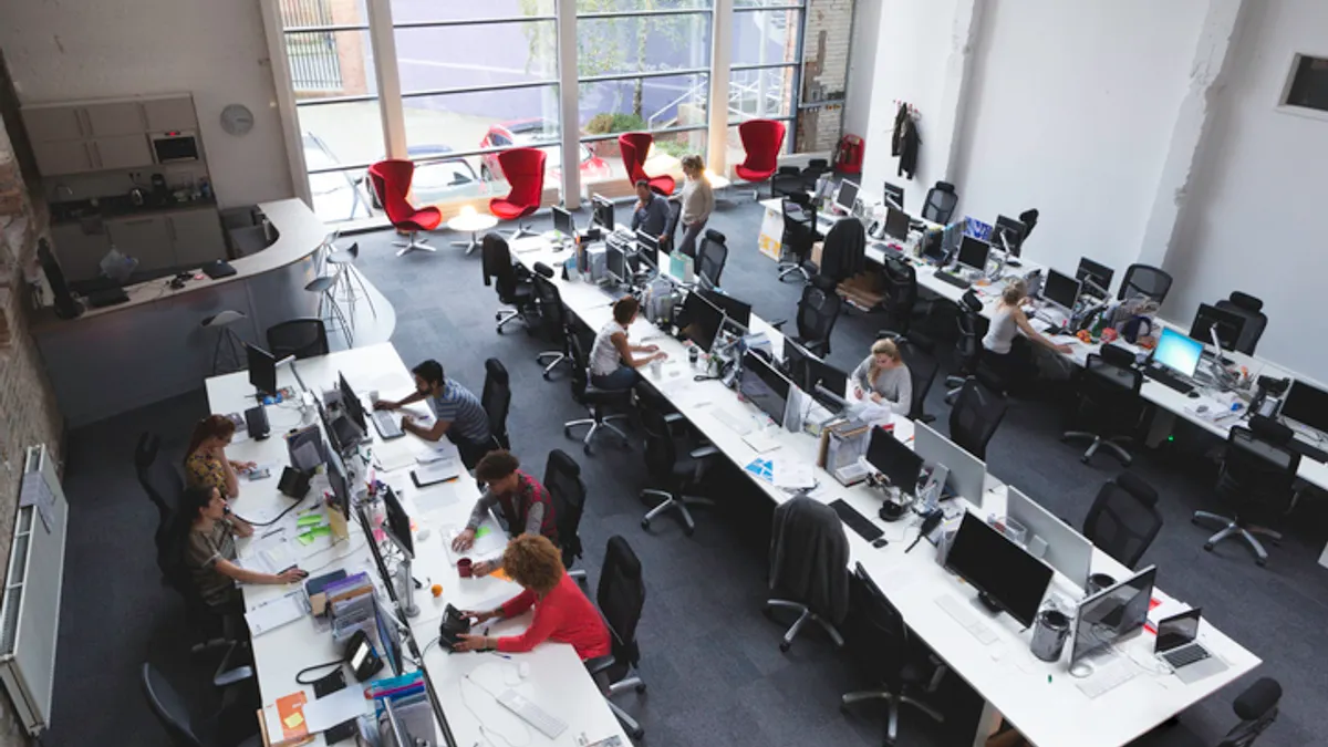 A large office seen from above with workers at multiple open workstations.