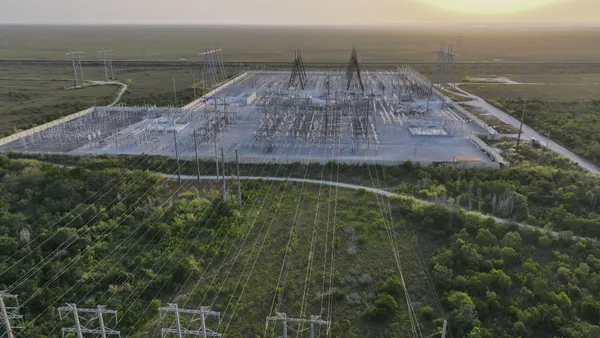 An electric substation with power lines in a grassy area.