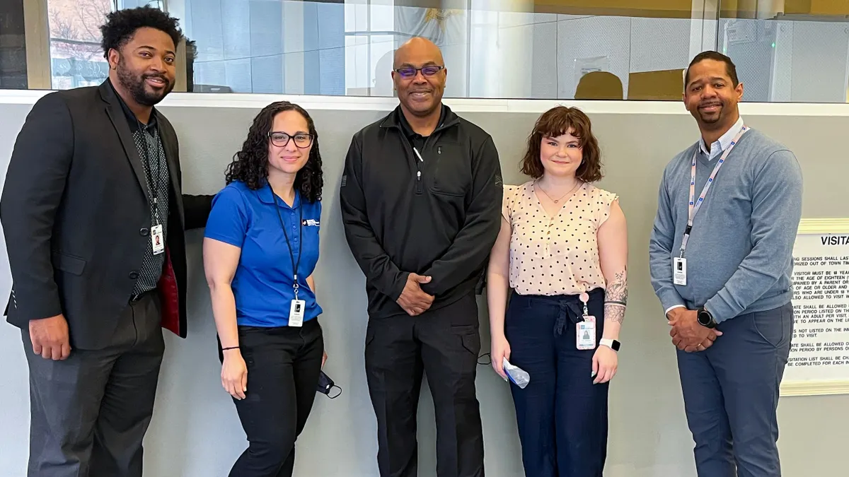 Five people standing in front of a wall.