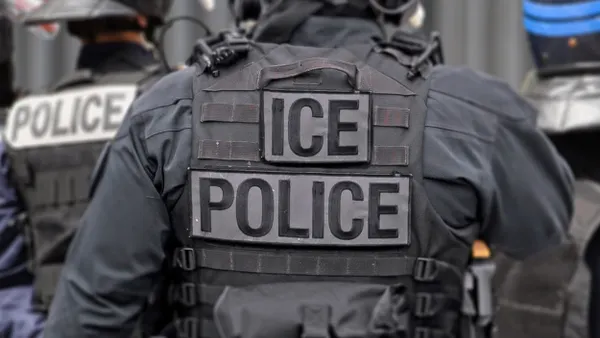 Back of officer with shirt that says POLICE ICE
