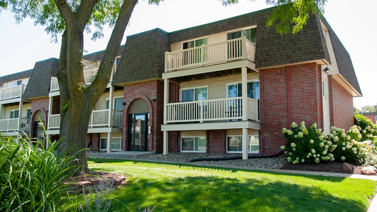 Three-level brick apartment building with brown patios.