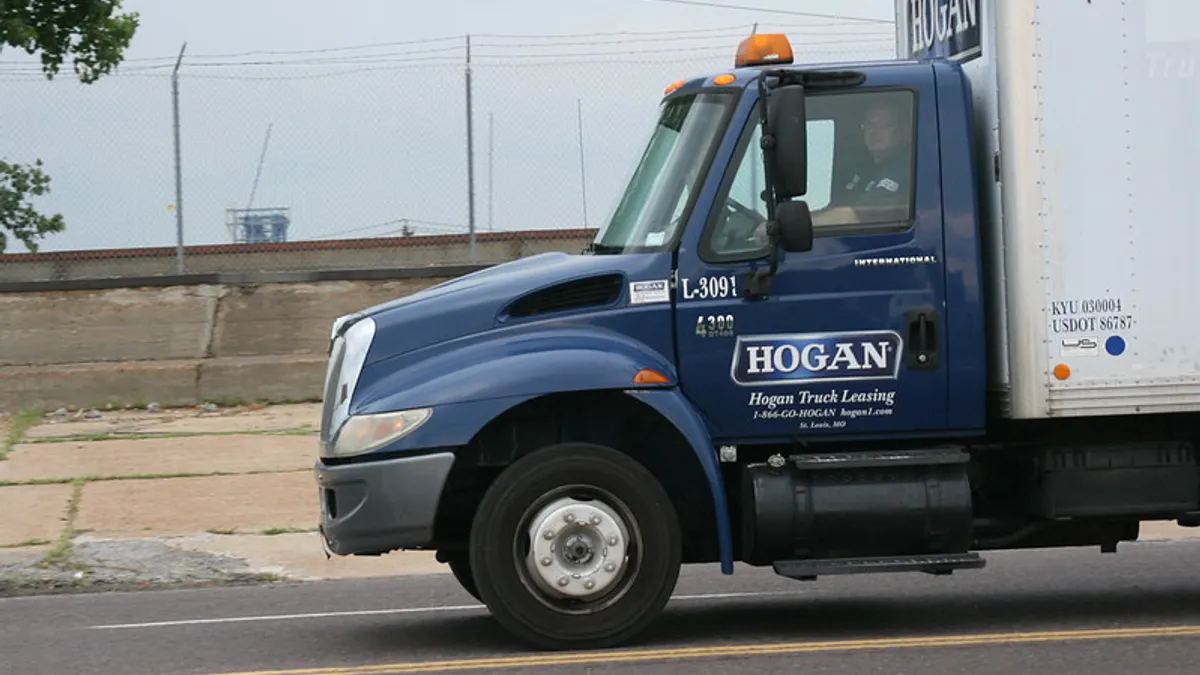 A Hogan truck on the roadway with a driver inside the vehicle.
