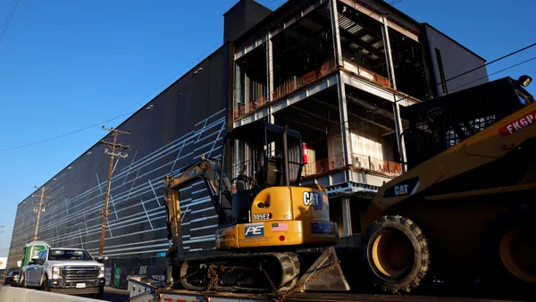 Construction equipment sits near a large building.