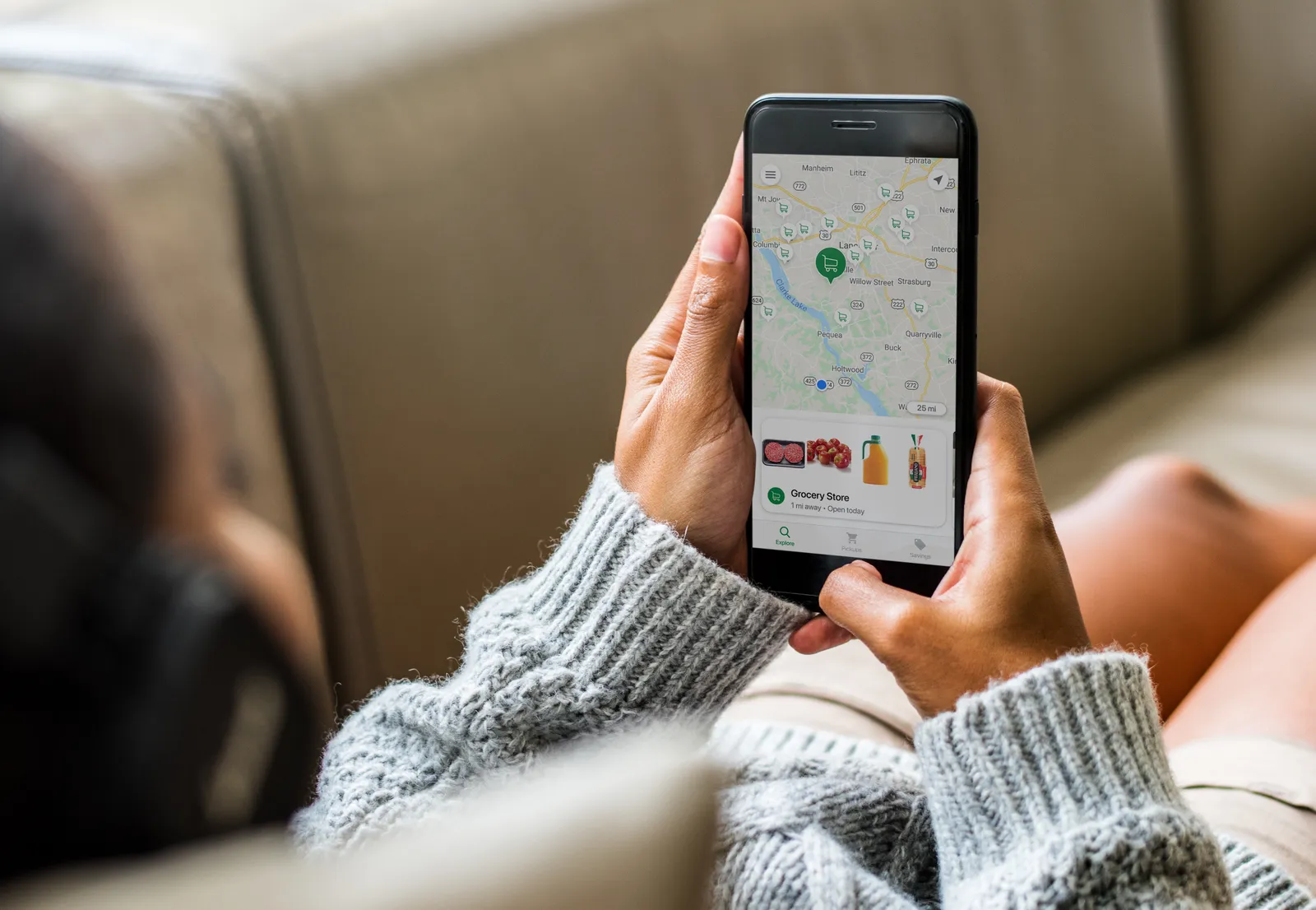 Close-up of hands holding a phone with the screen showing food items below a map