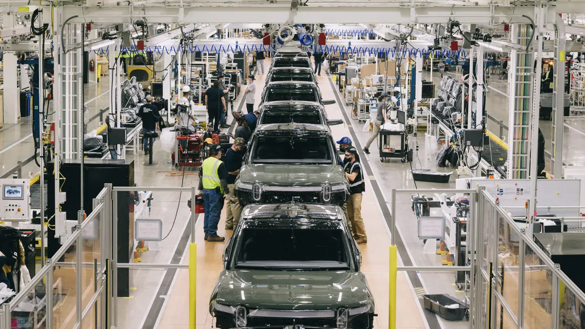 Assembly line workers installing parts on Rivian vehicles inside the company's factory in Normal Illinois.