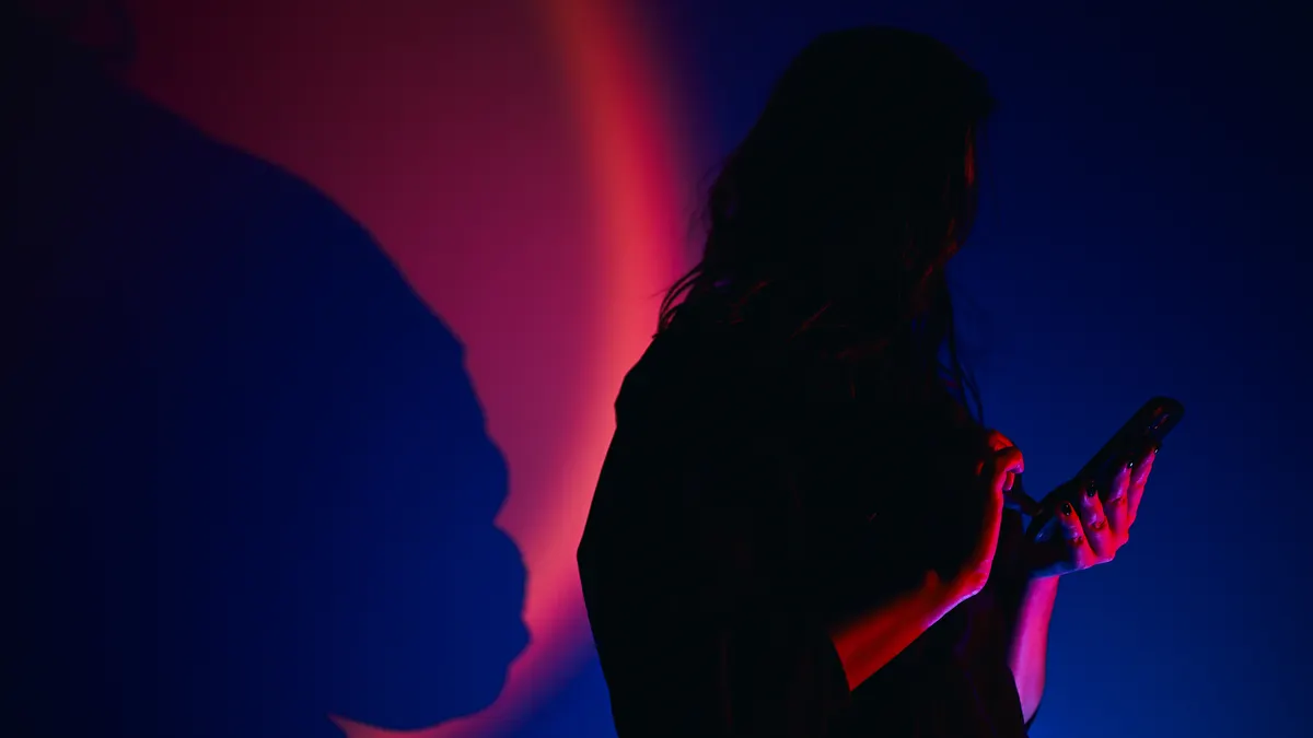 Woman silhouette using smartphone with neon light and shadow.