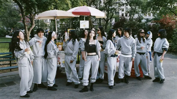A group of people in grey sweatpants and hoodies at an outdoor food stand.