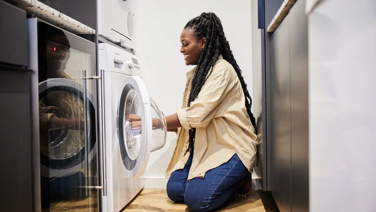 A woman putting laundry into the dryer