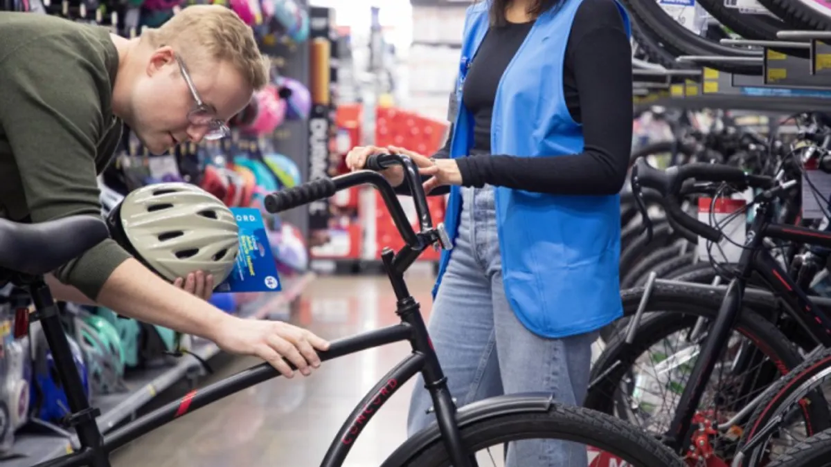 A customer leans over to inspect a bicycle on a rack inside a Walmart store