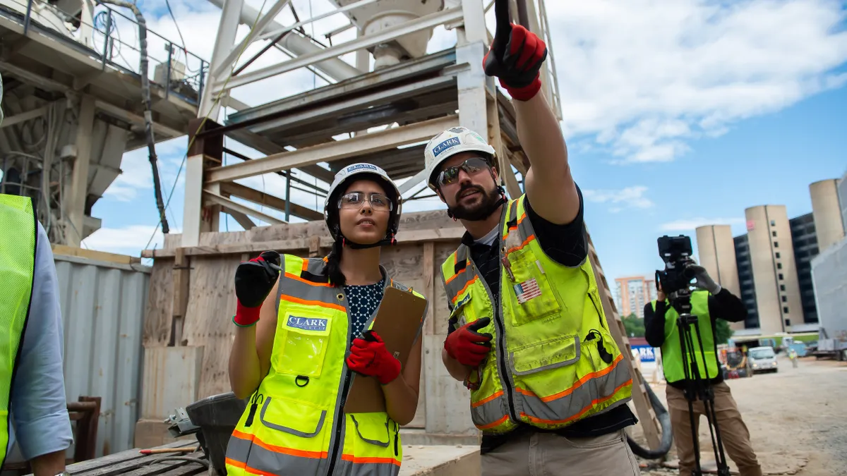 Two construction workers in bright safety gear examine a jobsite.