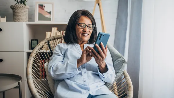 A woman uses a phone sitting on the couch.