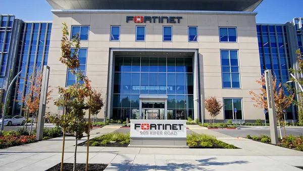 A building with large glass windows bears the Fortinet logo at the top, while a sign at ground level reads "Fortinet - 909 Kifer Road"