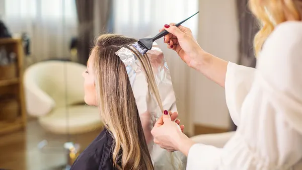 A hairdresser highlights a client's hair.