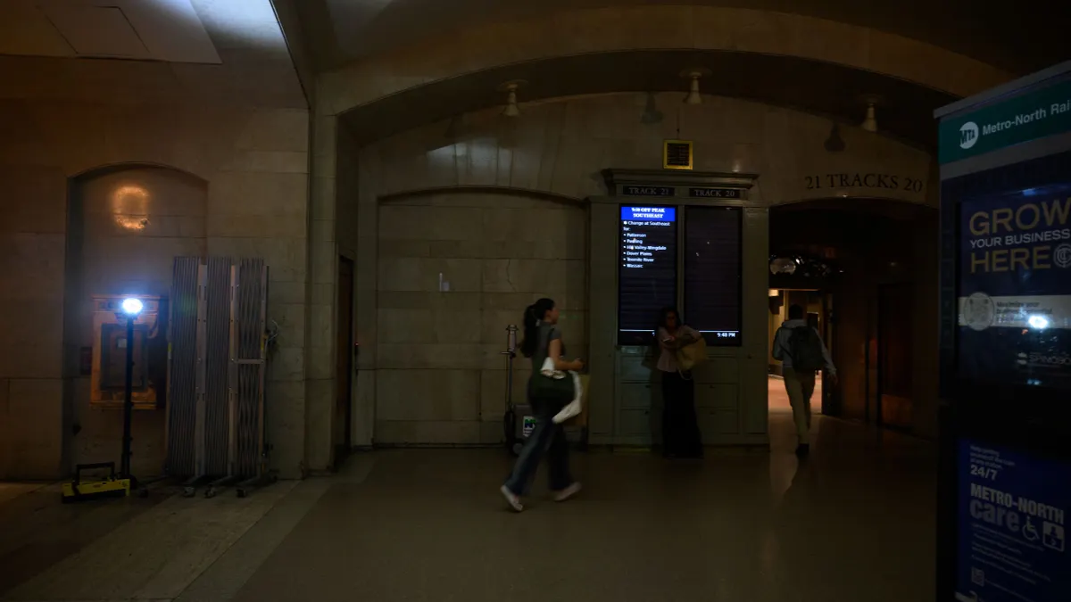 People walk through an area illuminated by a portable floor light in Grand Central Terminal following a power outage.