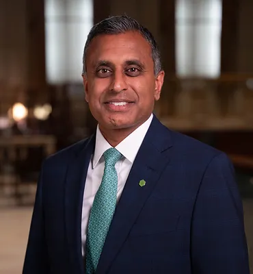 A person wearing a suit and tie smiles for the camera.