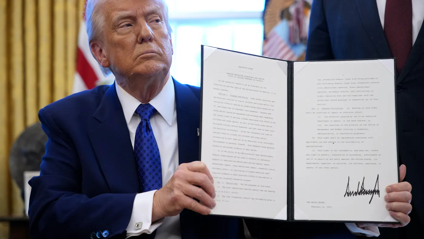 President Donald Trump holds a signed executive order