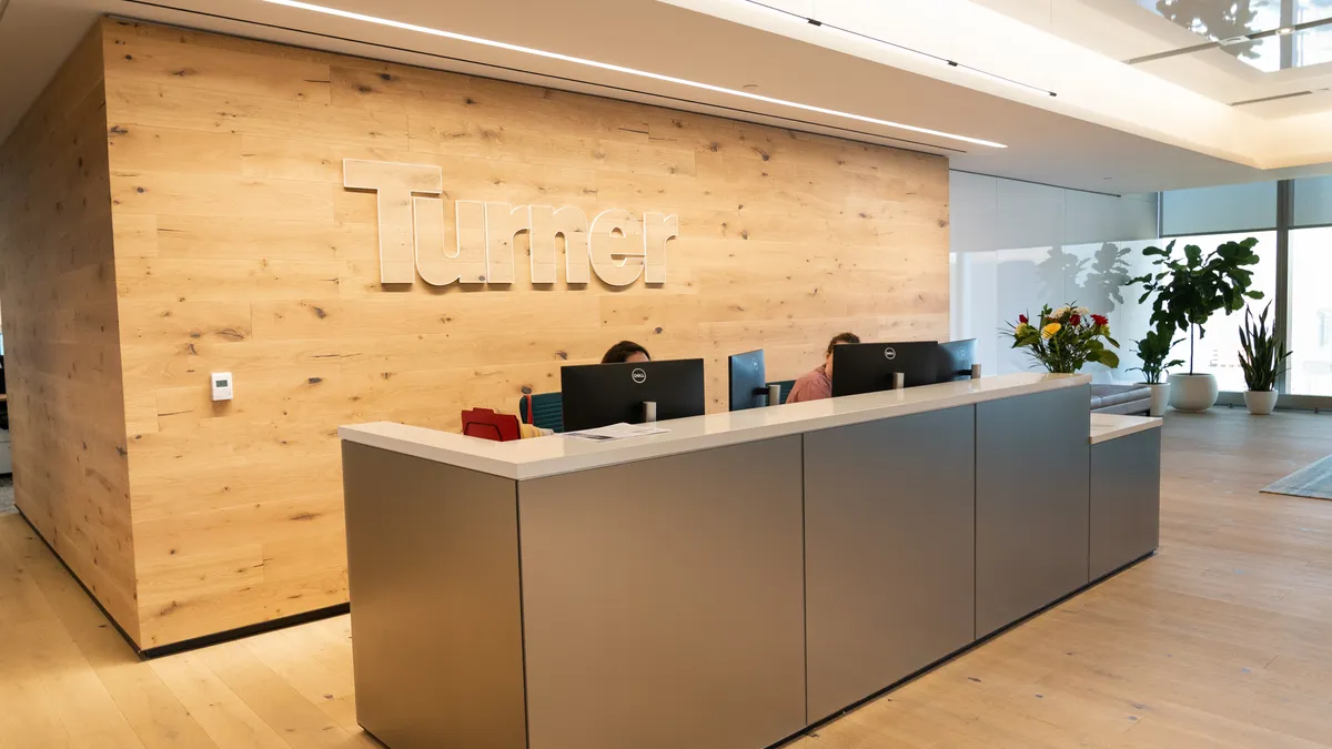 A photo shows the wood-paneled entrance to Turner Construction's headquarters in New York City.