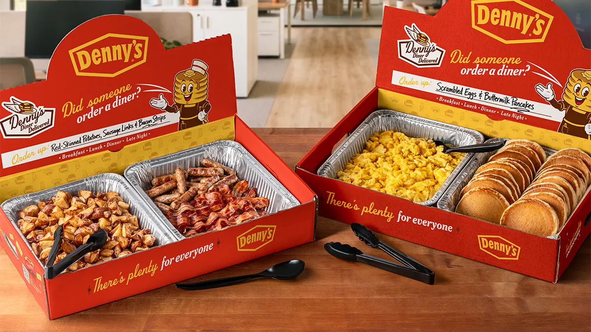 A photograph of two boxes on a table with various breakfast food items in aluminum pans.