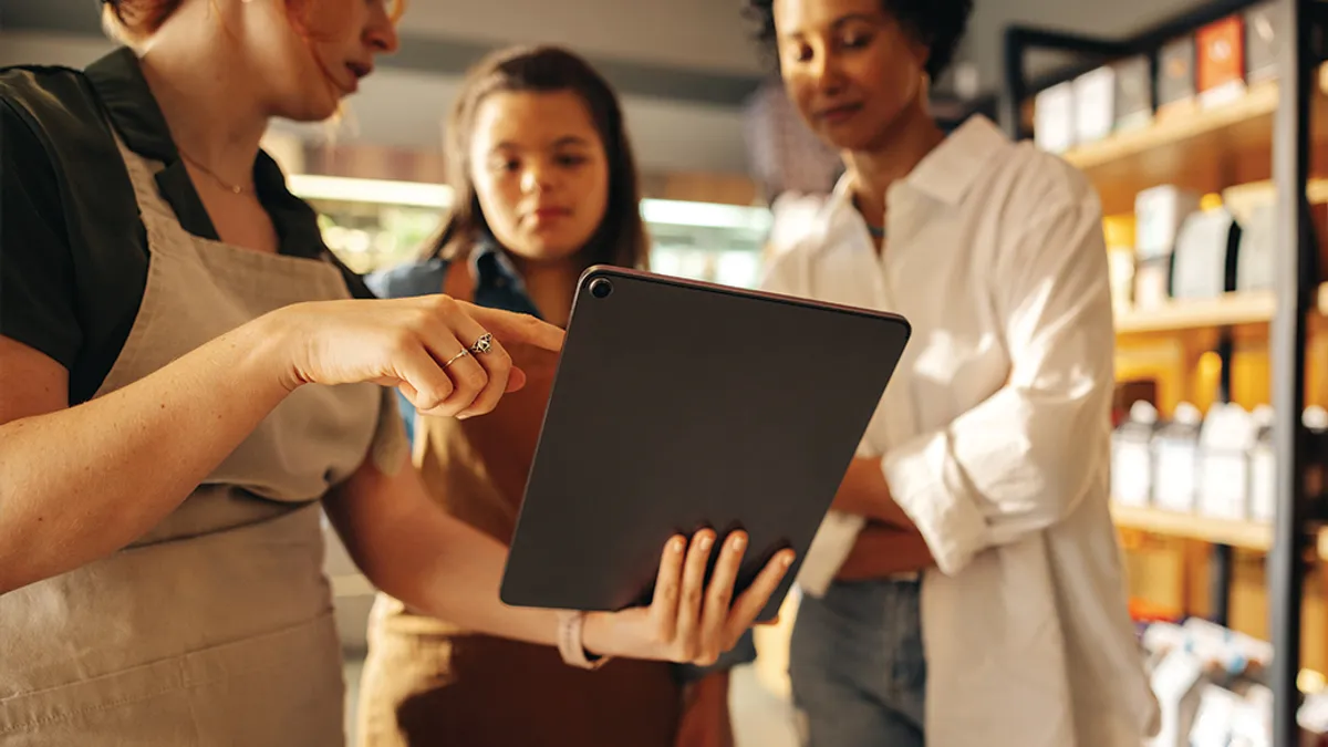 Grocery store manager using a digital tablet with her employees