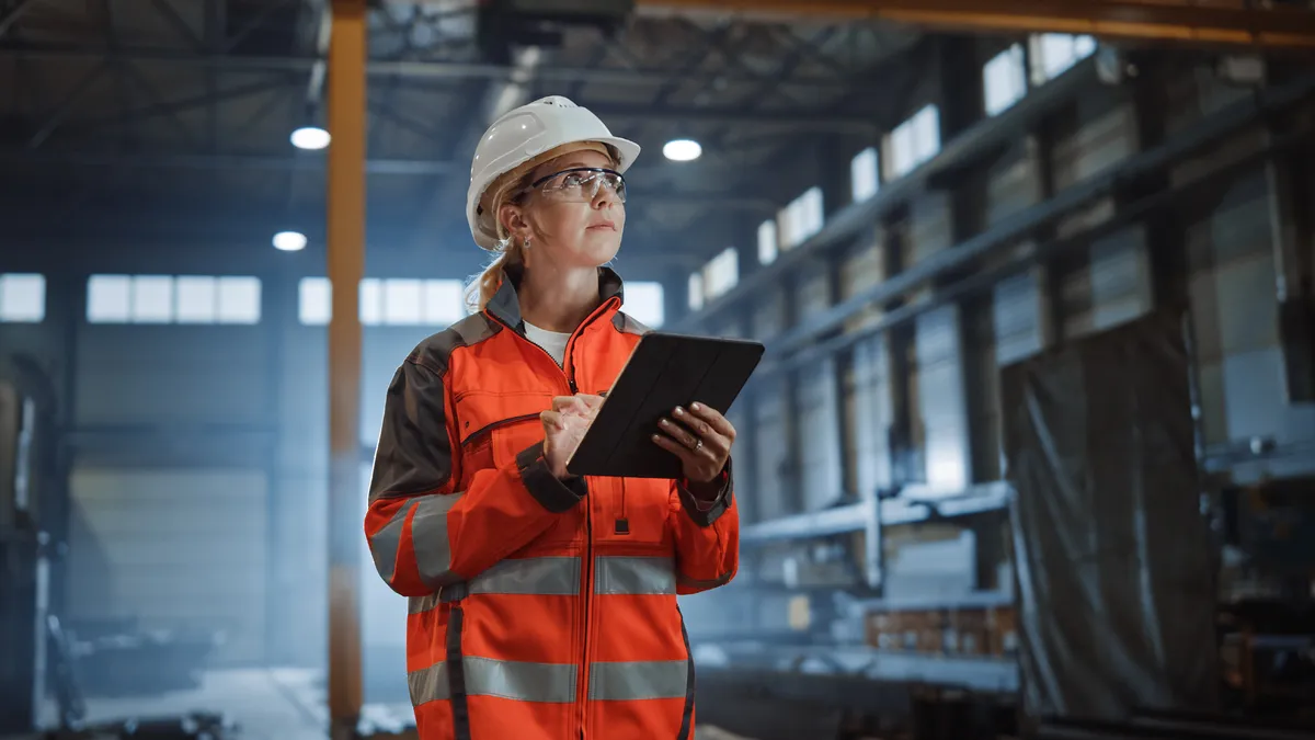 Heavy industry engineer worker wearing safety uniform and hard hat using tablet computer