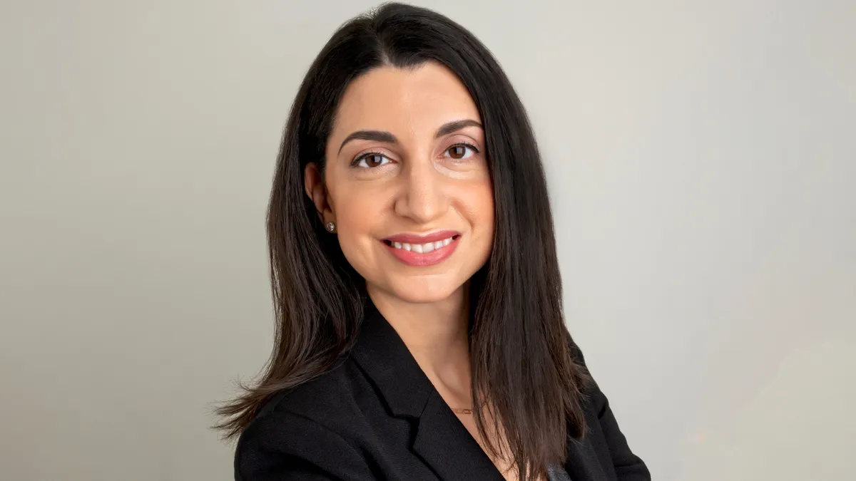 A person wearing a black suite smiles at the camera
