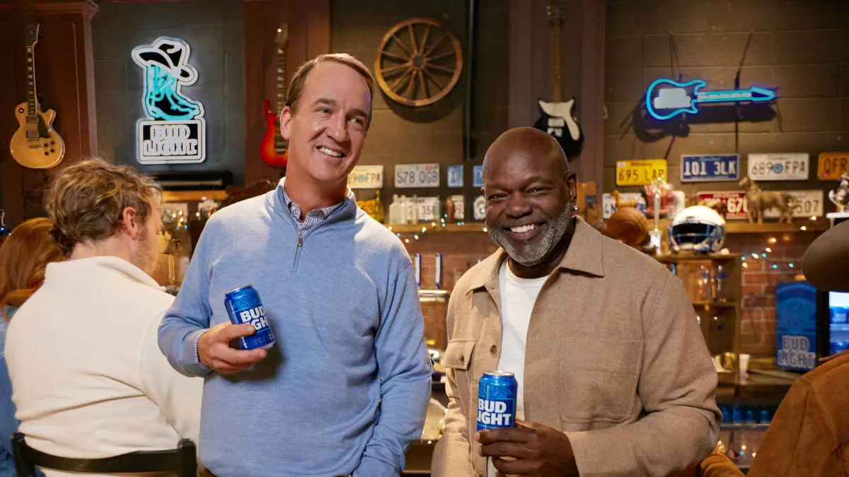 Peyton Manning and Emmitt Smith stand together holding cans of Bud Light.