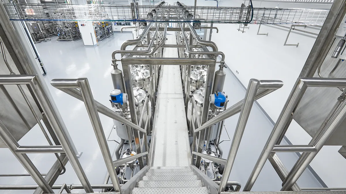 A view from a silver catwalk of Upside Foods' bioreactors in its EPIC facility and the stairs and walkway for people to access the tops of the machines.