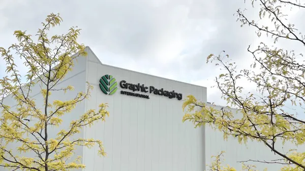An industrial facility with a white exterior and Graphic Packaging International's green and black logo.