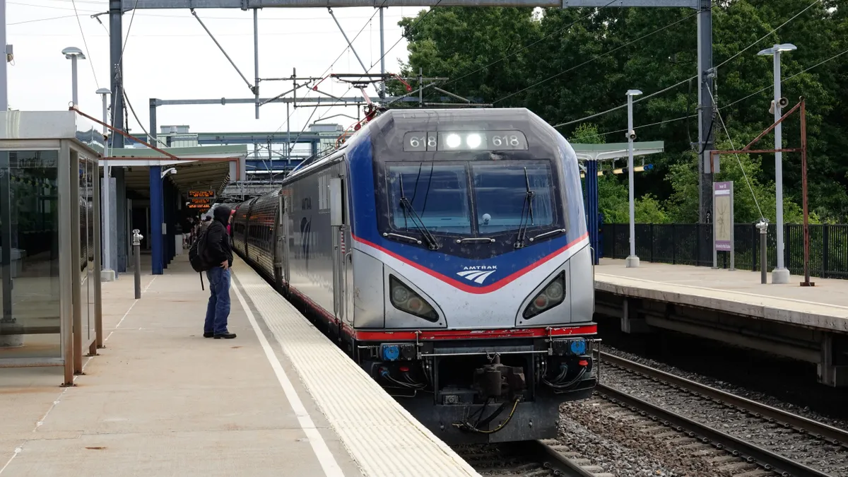 An Amtrak train at a station with people on the platform.