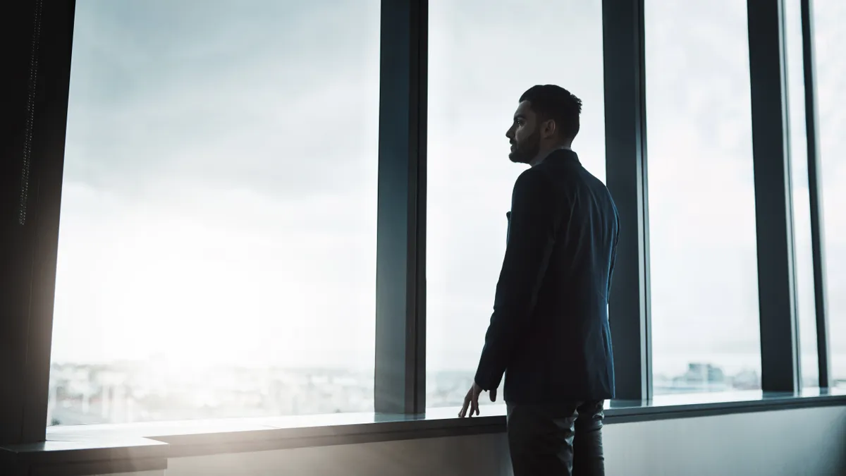 Business man looks out of an office window