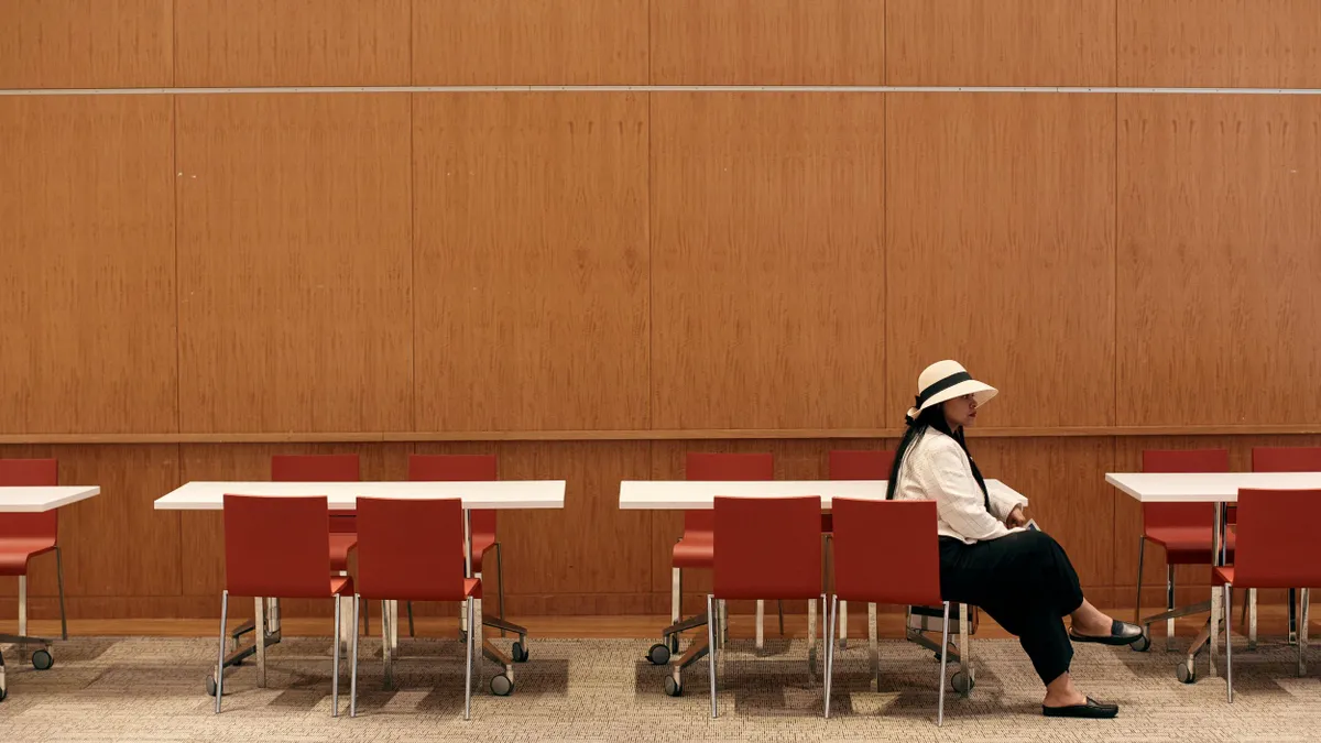 A person sits among a row of chairs.